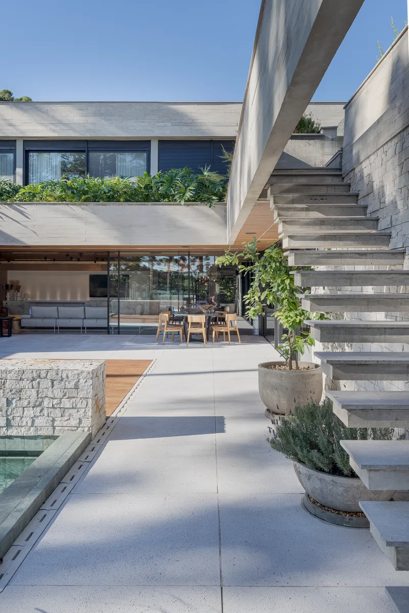 Cantilevered concrete staircase with planted risers overlooking covered terrace and pool edge