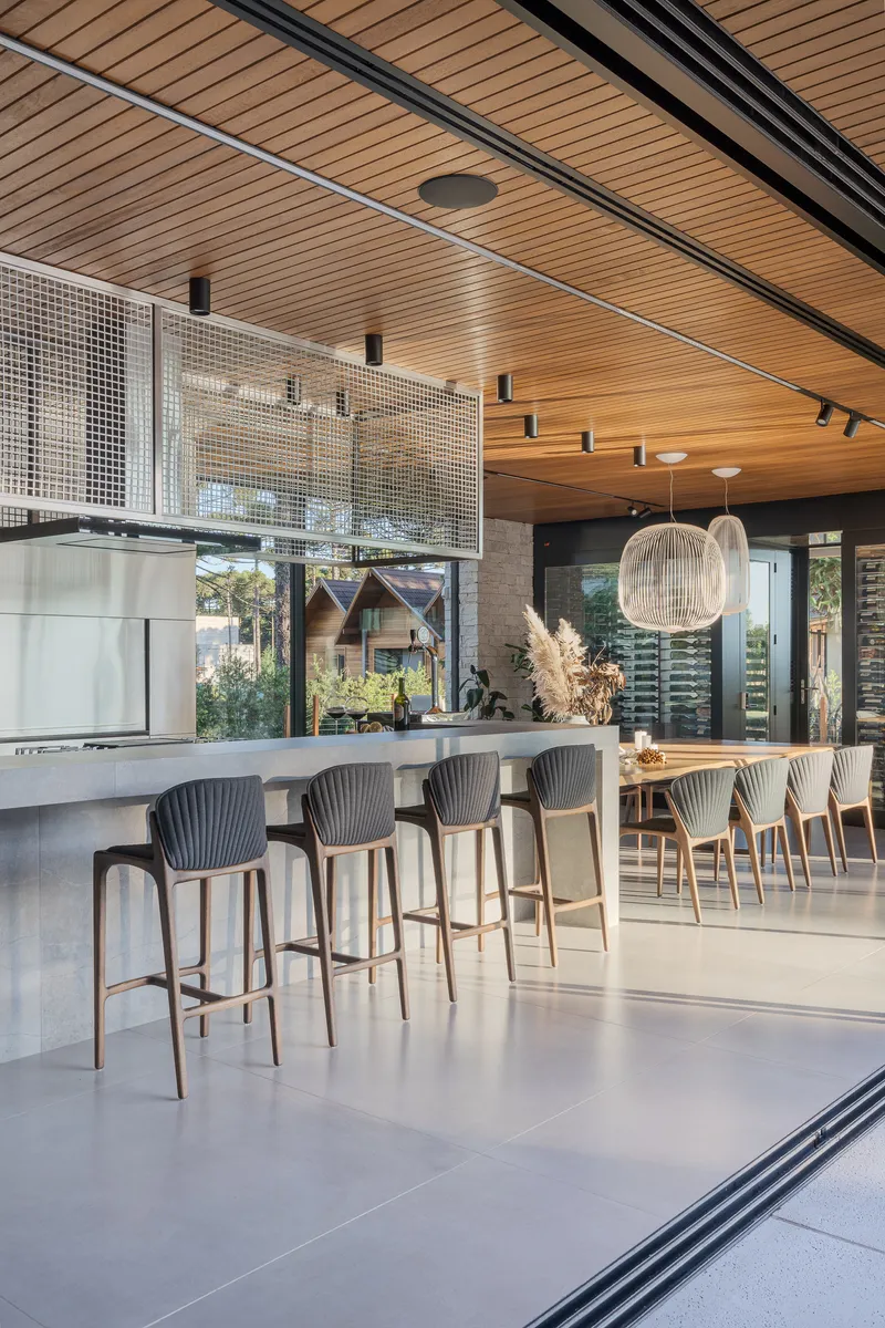Kitchen island with bar seating beneath a slatted wood ceiling and black track rails
