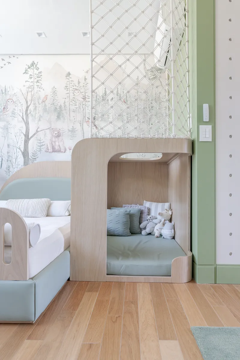 Curved timber play nook with built-in bed beneath wallpaper mural and mesh safety panel