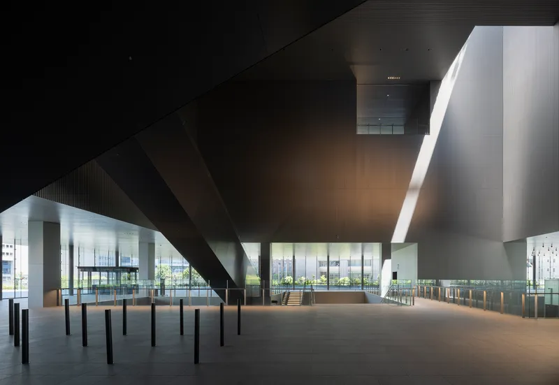 Ground level hall beneath a massive cantilevered ceiling slab supported by cylindrical columns
