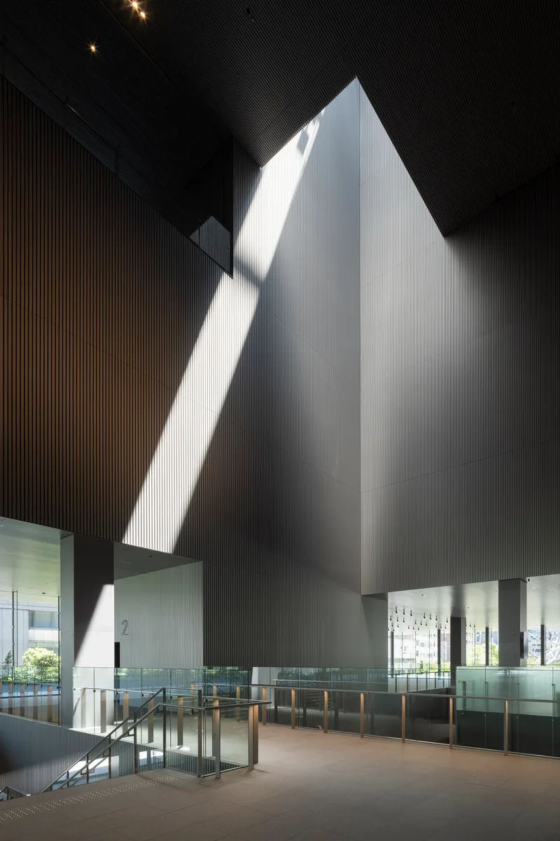Tall pyramidal volume illuminated by dramatic daylight slicing through the dark ribbed ceiling