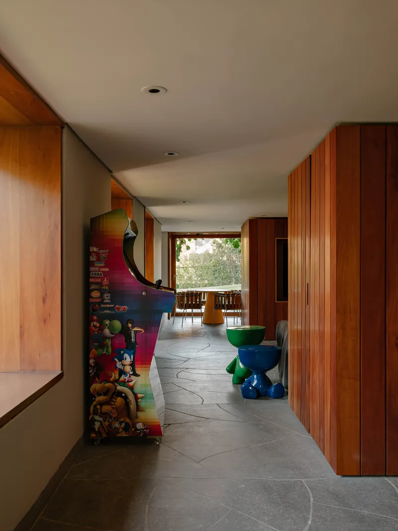 Gallery hallway with grey stone flooring leading to terrace framed by timber paneling and colorful artwork