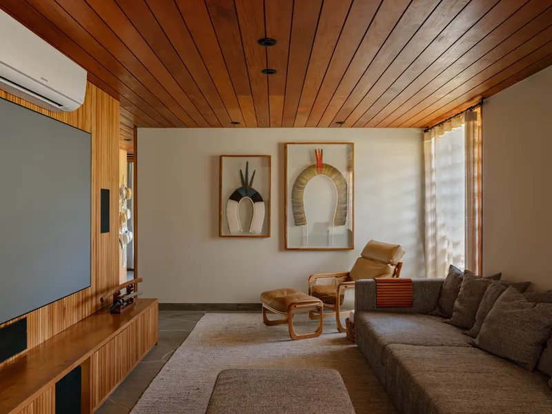 Living room with timber plank ceiling and framed artwork on white wall in afternoon light