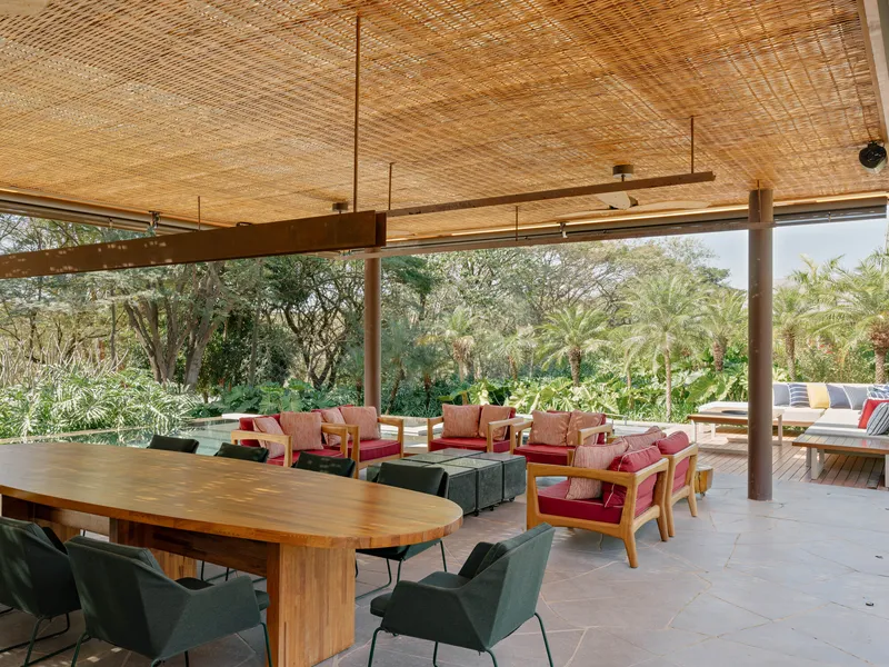 Covered terrace with woven bamboo ceiling and steel columns overlooking planted garden