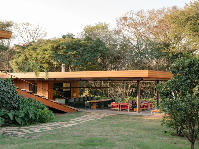 Rear courtyard showing the timber roof pavilion and exterior stair amid lawn and foliage