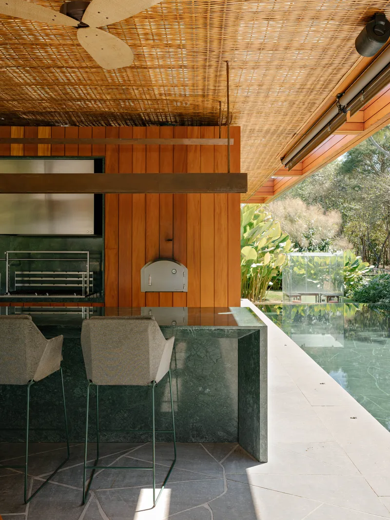 Kitchen counter with green marble base and timber wall beside reflecting pool edge at dusk