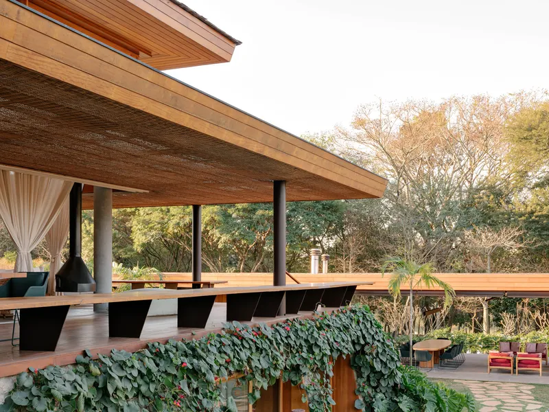 Elevated terrace with timber decking and woven timber ceiling overhang above vine-covered pergola below