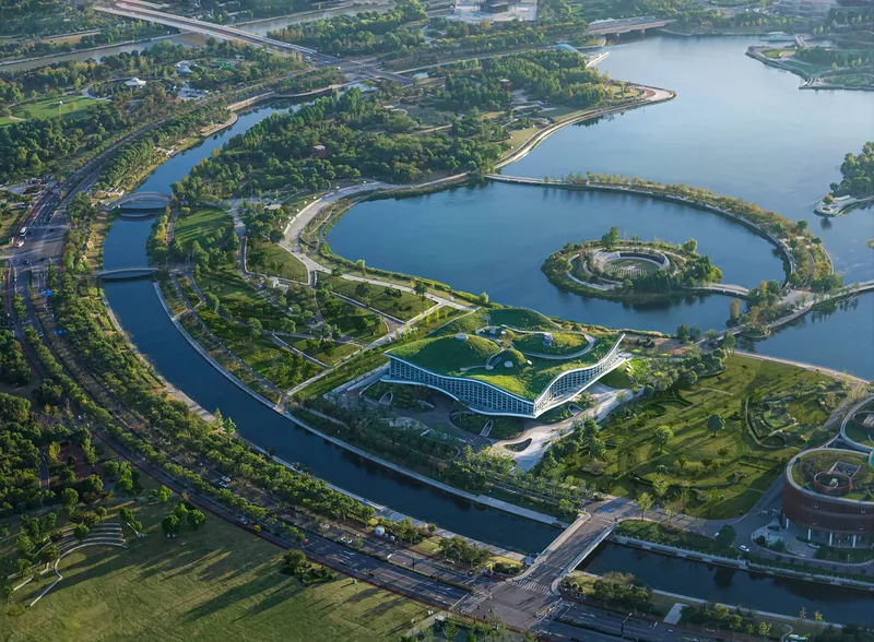Aerial view of the curving waterways and circular island with the building nestled in the green park landscape