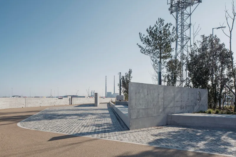 Curved concrete seating walls and paved plaza with communication tower and bare trees