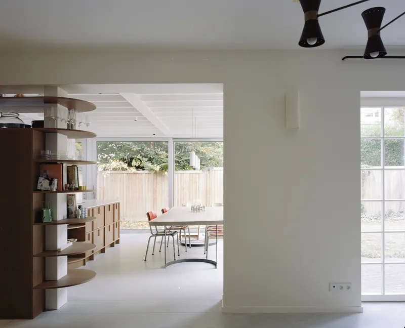 Open plan interior with curved timber shelving and view through to dining area and garden