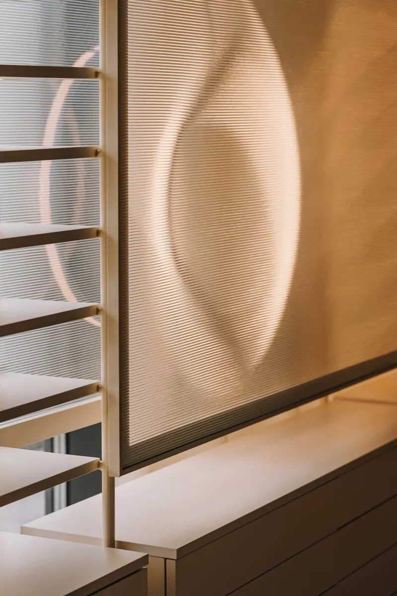 Shadow cast on ribbed translucent wall beside white display ledge in daylight