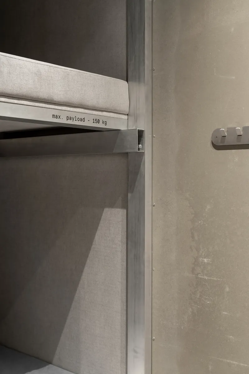 Industrial shelf unit with maximum payload label against concrete wall with exposed fasteners