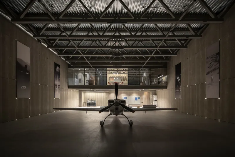 Tail view of aircraft centered in the hangar with mezzanine level visible at the rear