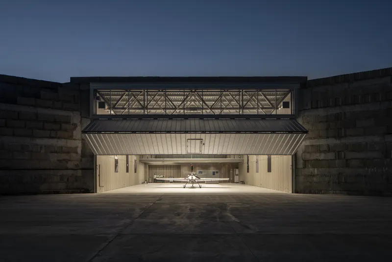 Frontal view of the illuminated hangar opening framed by concrete walls at twilight