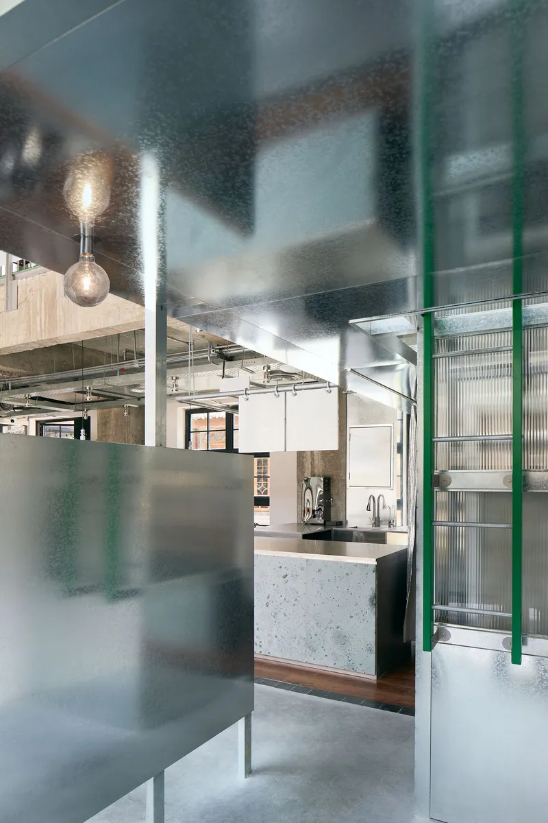 Translucent glass partition panels framing a view to the concrete bar counter and exposed ductwork beyond