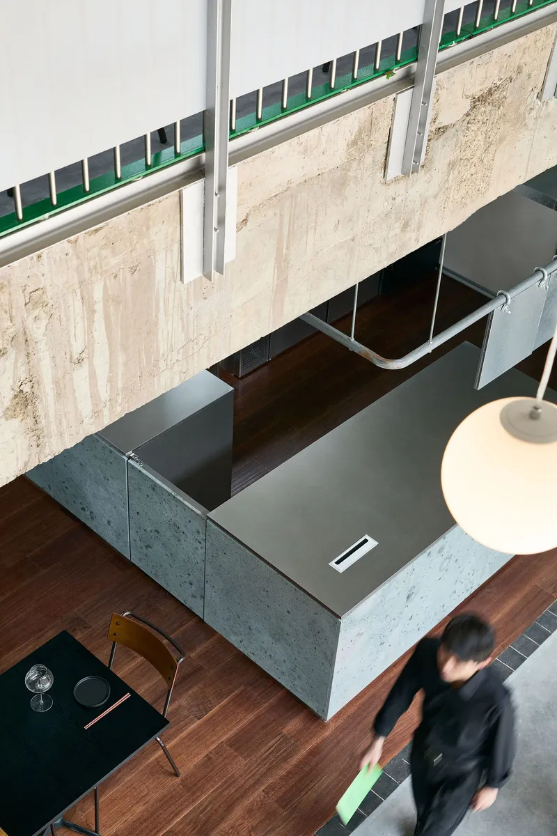 Top-down view of the concrete reception counter with walnut trim and a person passing below