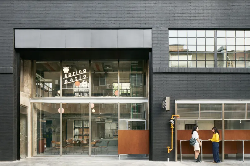 Street-level facade with dark brick cladding and double-height glazed entrance with two figures conversing