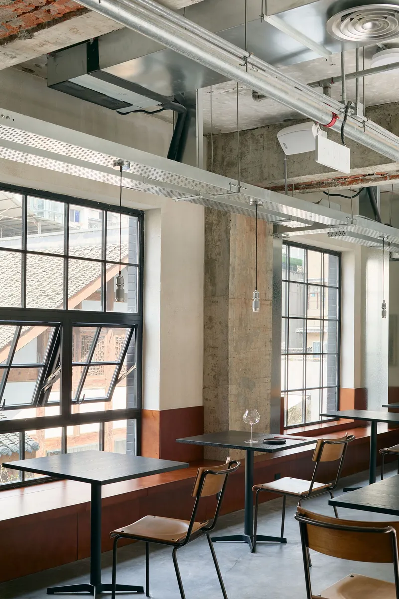 Dining area with exposed concrete columns, steel-framed windows, and terracotta tile wainscoting