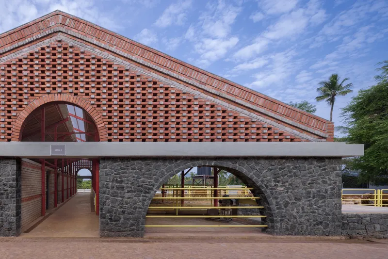 Brick gable with perforated pattern and arched window over stone arcade with palm trees behind