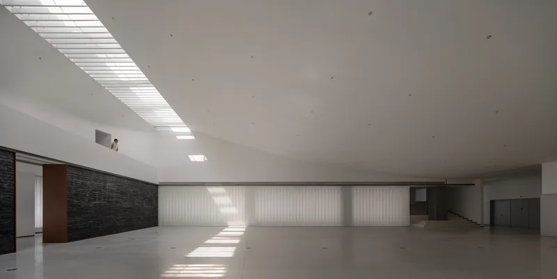 Gallery interior with linear skylight casting sharp shadows across the polished concrete floor