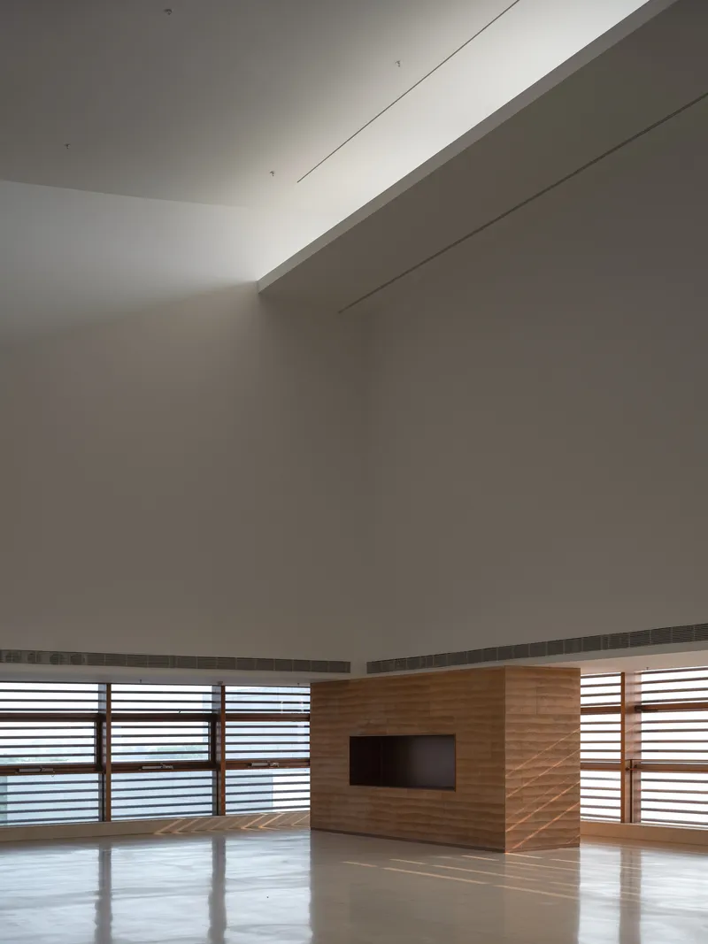 Interior room with wood-clad wall housing a recessed screen and horizontal louvered windows