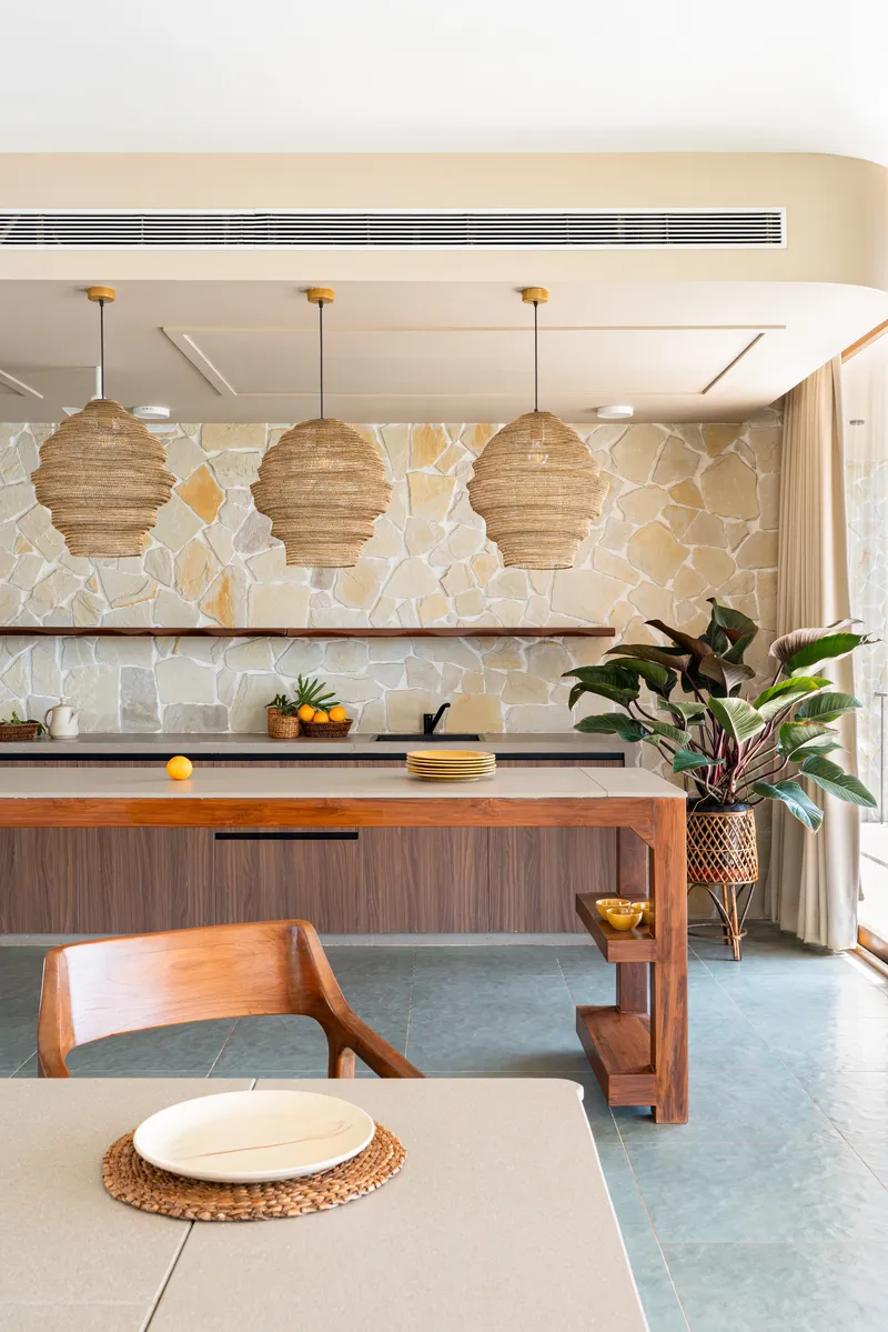 Kitchen with irregular stone backsplash and three tiered woven pendant lights above the island