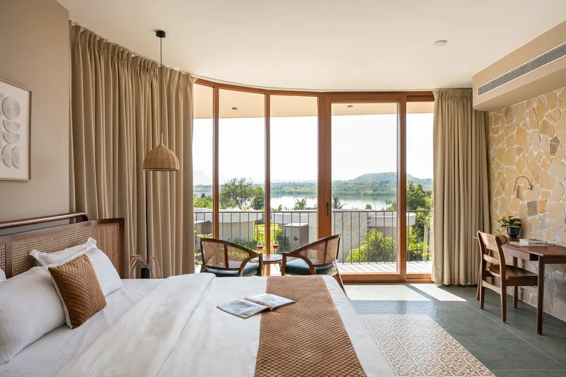 Bedroom with curved glazed doors opening to a planted terrace with lake views beyond
