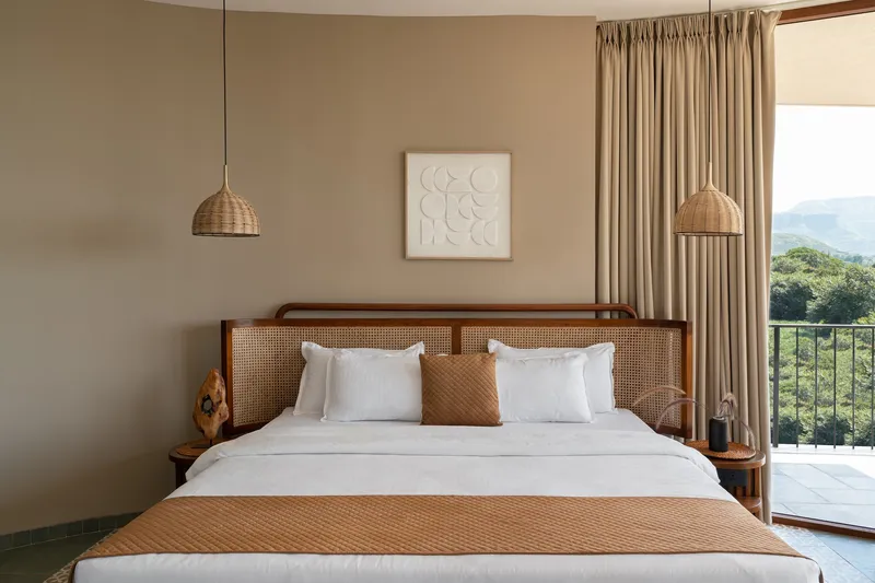 Bedroom with cane headboard and woven pendant lights framing a view to distant mountains