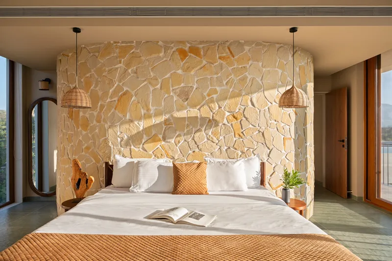 Carved limestone feature wall behind the bed with integrated lighting and suspended pendant fixtures