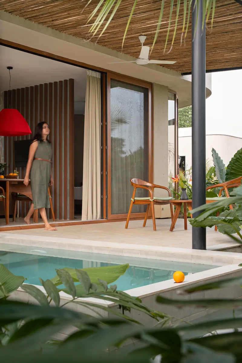 Covered terrace with woven bamboo ceiling, steel column, and a figure stepping through sliding doors