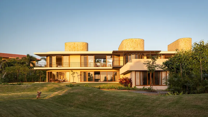 Garden facade with three cylindrical cork-clad towers and horizontal bands of glazing at sunset