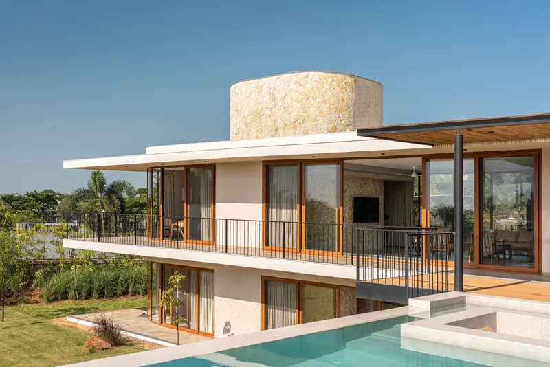 Poolside view of stacked terraces with cantilevered roof planes and a stone tower volume