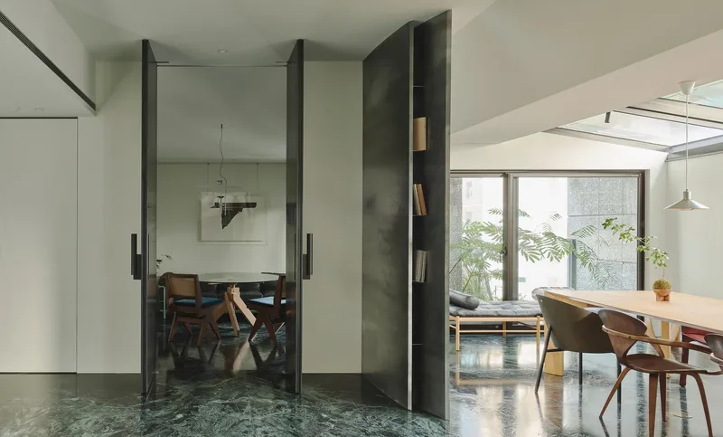 This architectural image showcases a modern interior with a focus on clean lines and natural light. The space features a dining area with a wooden table and cha