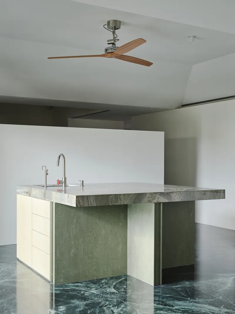 This architectural image showcases a modern kitchen island with a stone countertop and wood cabinetry, set against a marble floor. The design emphasizes clean l
