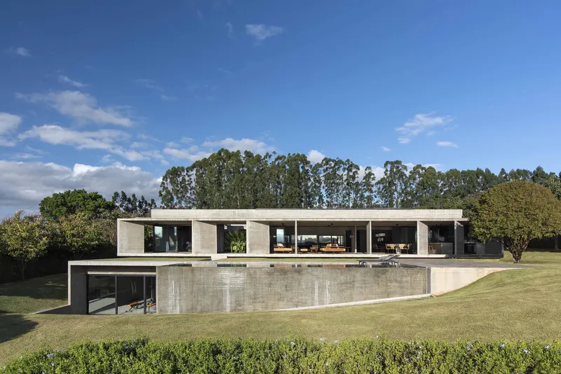 Horizontal concrete residence overlooking a lawn with eucalyptus trees under a partly cloudy sky