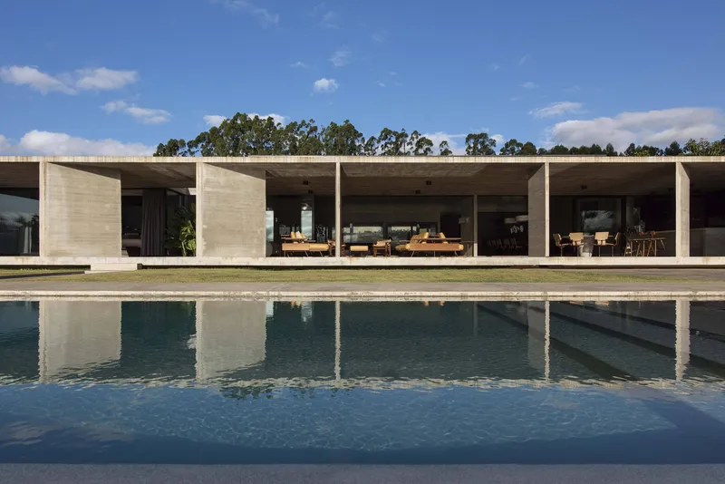 Boardmarked concrete colonnade reflected in a swimming pool with the terrace in full sun