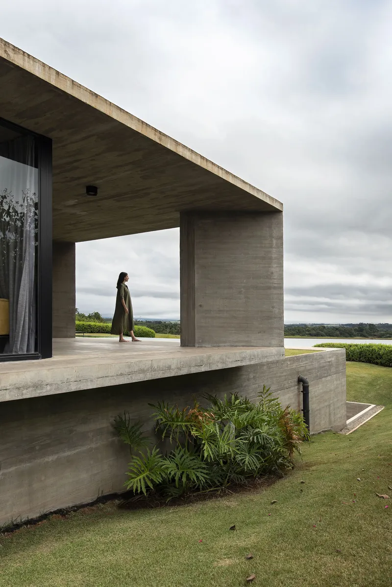 Elevated terrace with boardmarked concrete overhang and a figure standing beneath an overcast sky