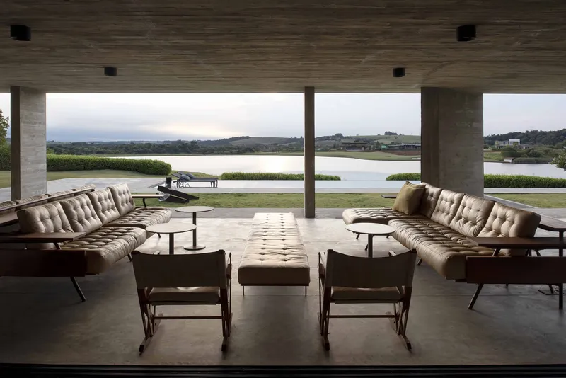 Open-air lounge space with tufted seating and rocking chairs facing the water at dusk