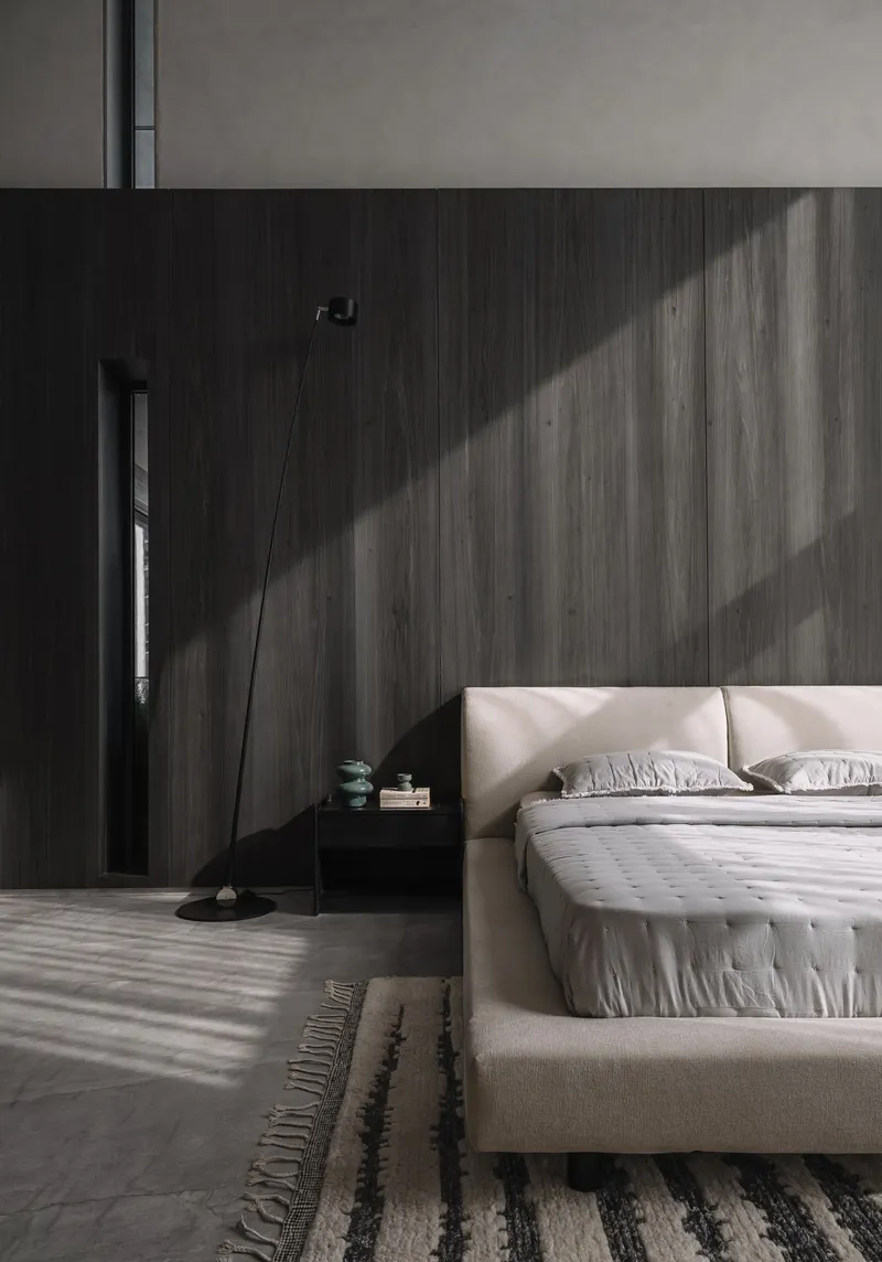Dark wood wall in a bedroom with striped shadows cast by natural daylight through unseen blinds