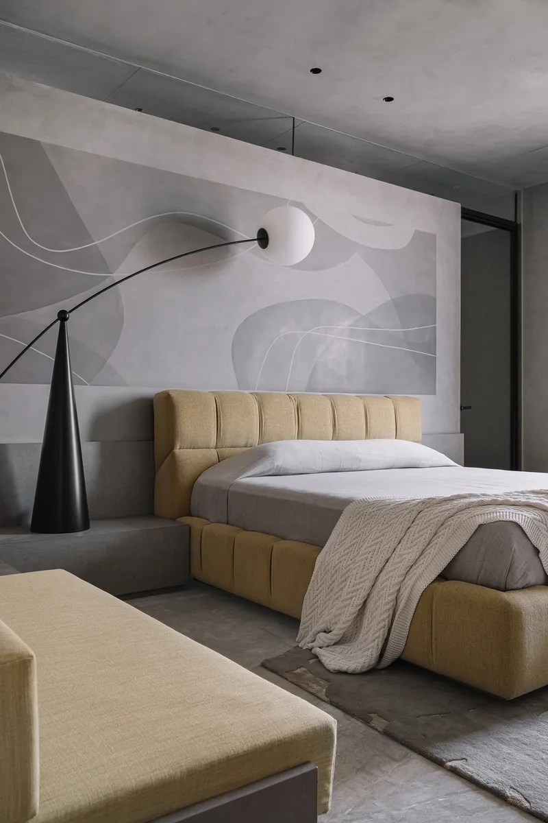 Bedroom with tufted yellow bed frame against a wall mural of flowing abstract forms in soft grey