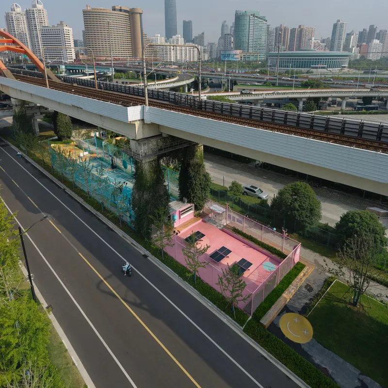 Aerial view of the pink sports court nestled between highway infrastructure and adjacent roadways