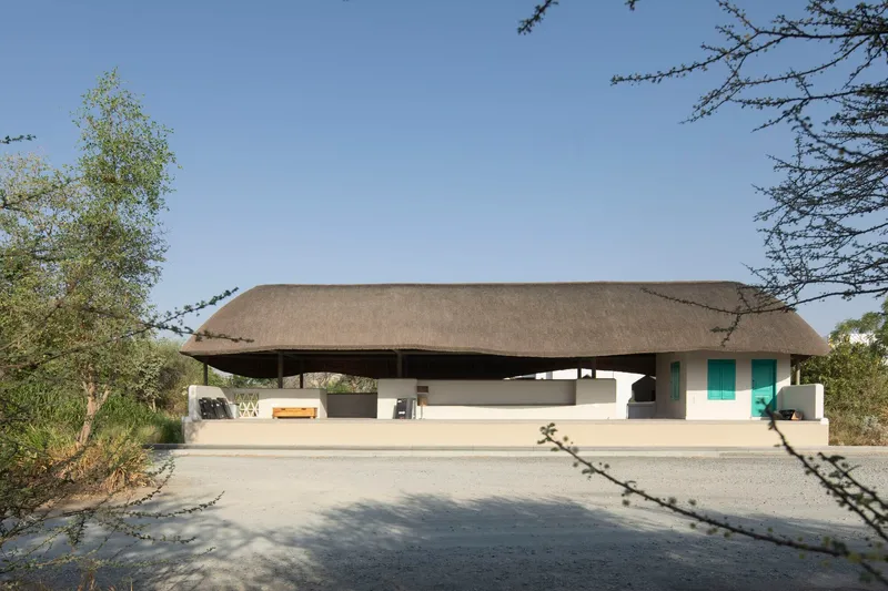 Front view of the sweeping thatched roof canopy floating above white rendered walls framed by bare trees