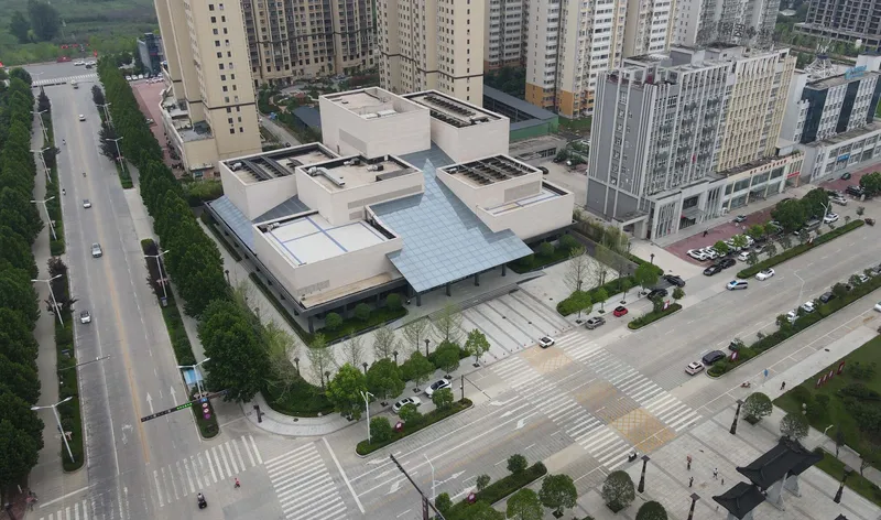 Aerial view of the low-rise complex with glazed roof among residential towers and tree-lined streets