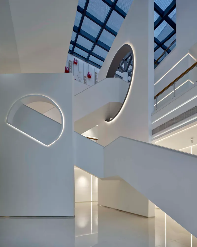 Curved white staircase with integrated LED lighting rising through the multi-level atrium