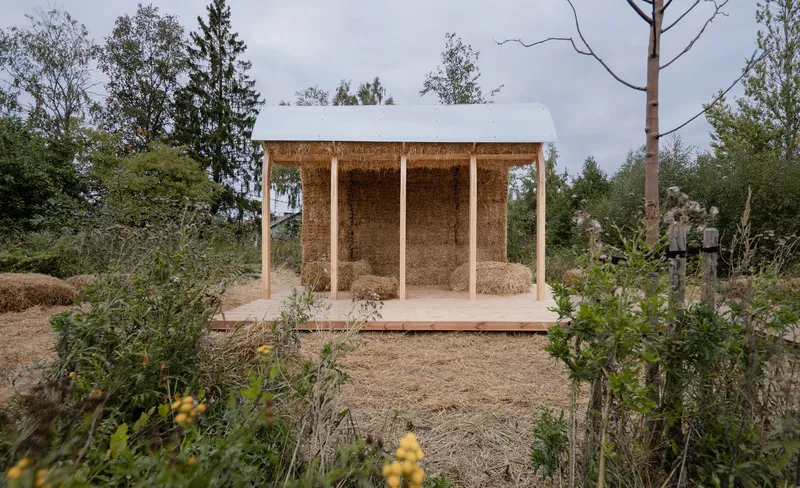 Front view of the pavilion showing three arched straw bale bays framed by timber posts and beams