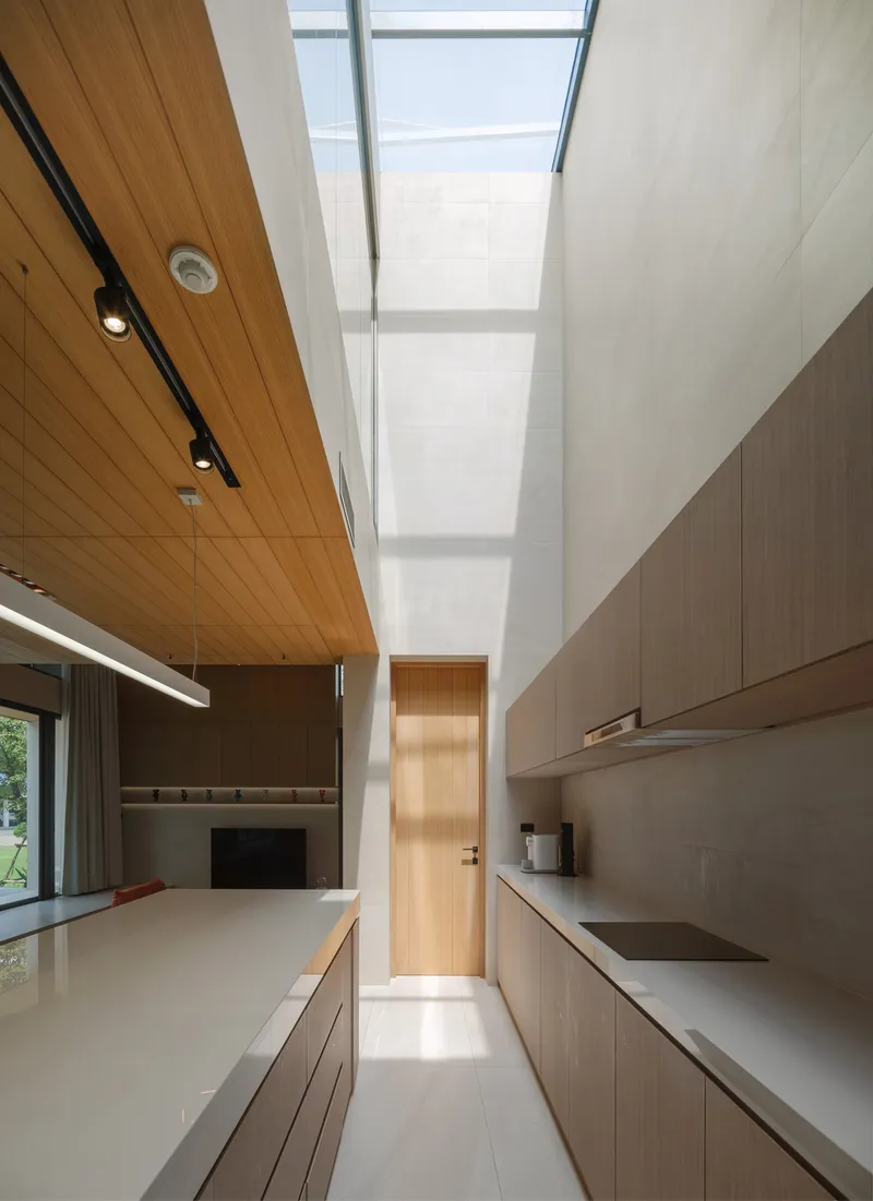 Kitchen interior with skylight overhead and timber door visible at the corridor's end