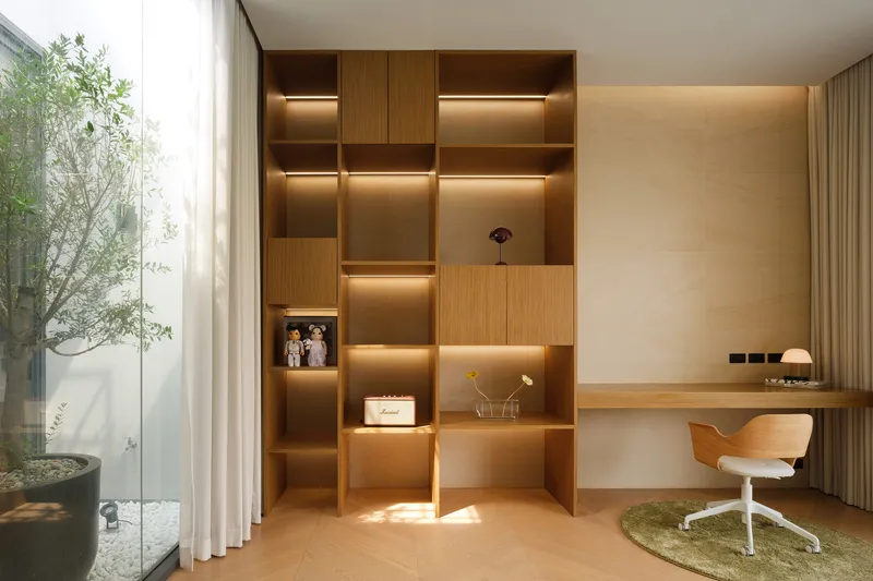 Study nook with illuminated timber shelving and view to the planted courtyard through glass