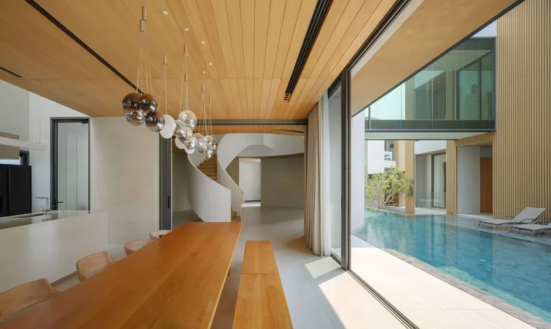Dining room with timber ceiling and glass pendant lights overlooking a courtyard pool