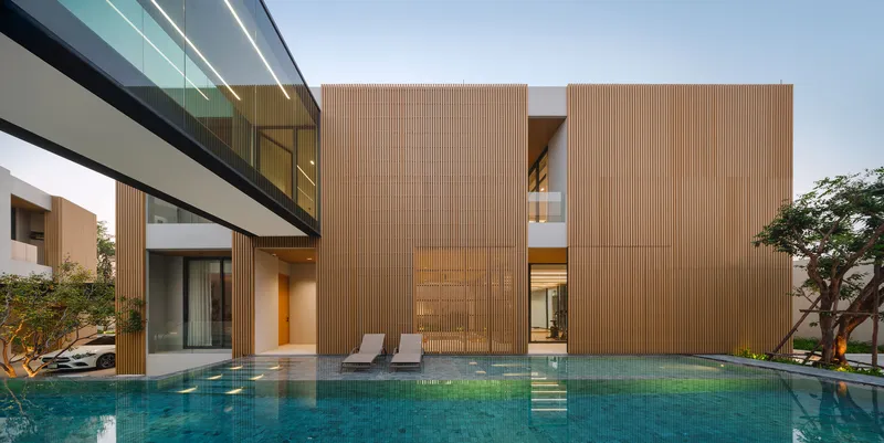 Courtyard pool with stepping stones facing the vertical timber-clad facade at dusk