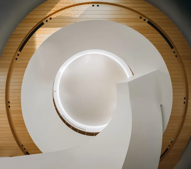 Overhead view of the spiral staircase with timber ceiling wrapping the white curved walls and handrail